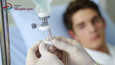 Пациент лежит под капельницей, врач поправляет капельницу